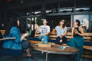 Four Women Chatting While Sitting on Bench