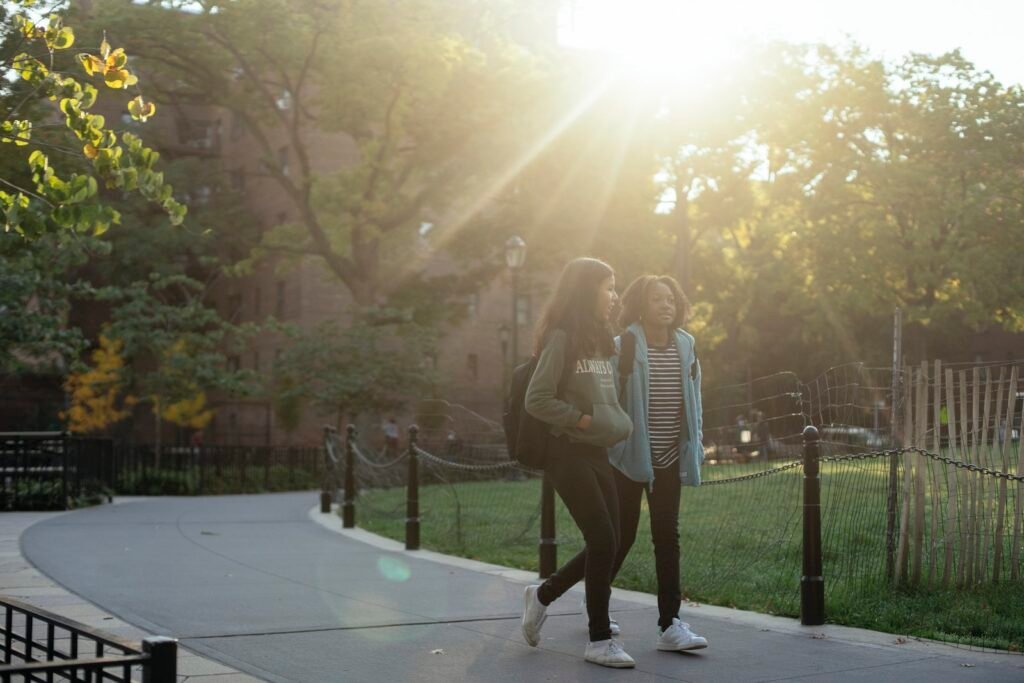 Multiracial schoolgirls walking in park during sunny day