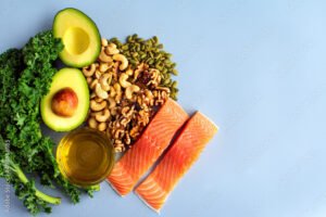 Overhead View of Fresh Omega-3 Rich Foods: A variety of healthy foods like fish, nuts, seeds, fruit, vegetables, and oil rich in omega-3 nutrients