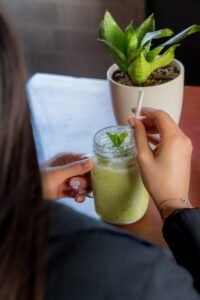 person holding clear drinking glass with green liquid